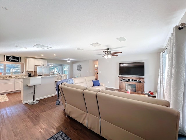 living room featuring ceiling fan and dark hardwood / wood-style floors