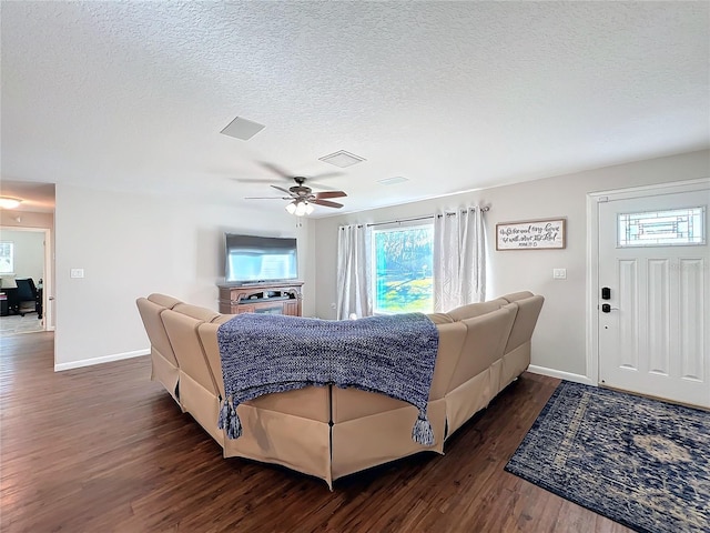 living room with ceiling fan, dark hardwood / wood-style flooring, and a textured ceiling