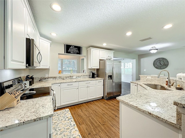 kitchen featuring white cabinets, sink, light wood-type flooring, a textured ceiling, and stainless steel appliances