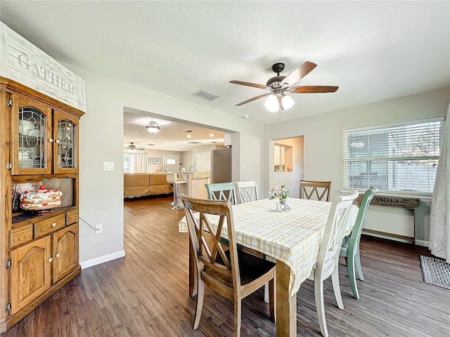 dining room with a textured ceiling, ceiling fan, and dark wood-type flooring