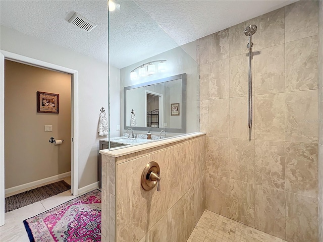 bathroom with a tile shower, a textured ceiling, and tile patterned floors