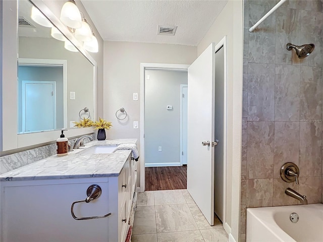 bathroom featuring a textured ceiling, vanity, and tiled shower / bath combo