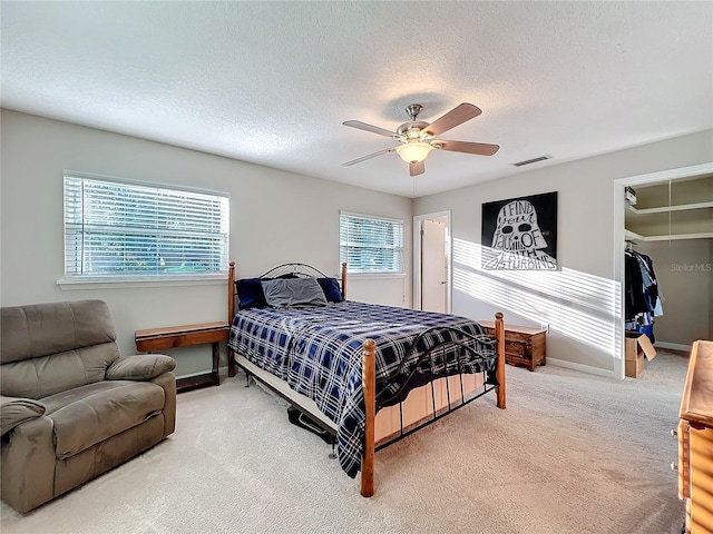 carpeted bedroom with a spacious closet, a closet, ceiling fan, and a textured ceiling