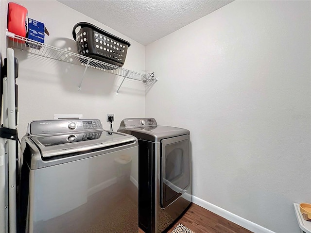 laundry room with washer and dryer, wood-type flooring, and a textured ceiling