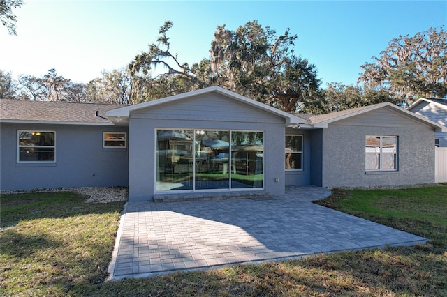 back of property with a yard and a patio