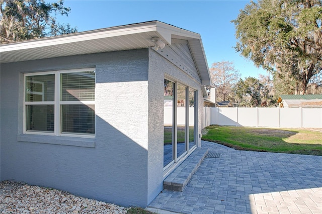 view of side of property with a patio and a lawn