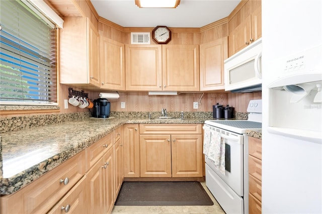 kitchen featuring light brown cabinetry, white appliances, light stone counters, and sink