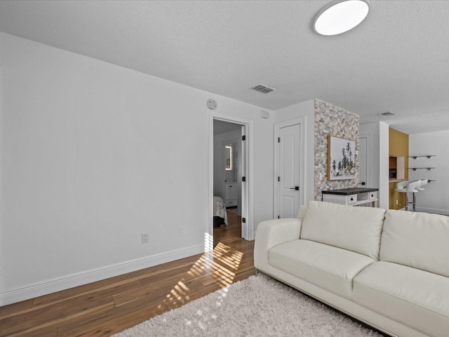 living room featuring dark wood-type flooring and a textured ceiling