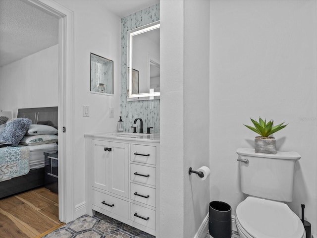 bathroom featuring vanity, wood-type flooring, a textured ceiling, and toilet