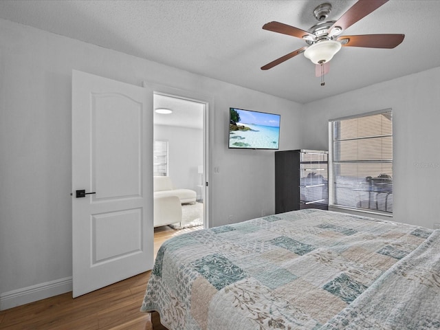 bedroom with a textured ceiling, hardwood / wood-style flooring, ensuite bath, and ceiling fan