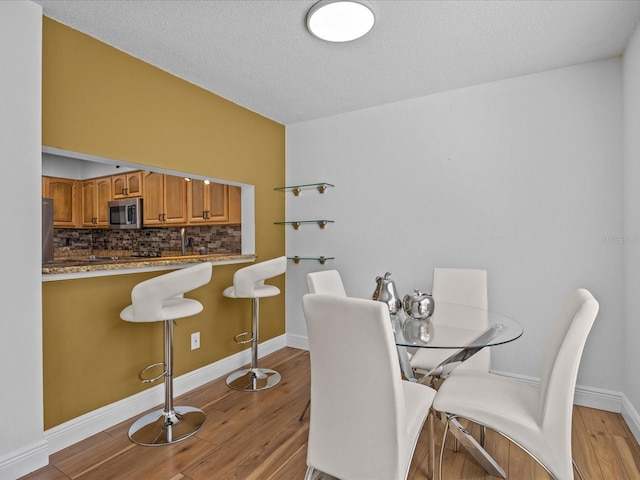 dining area with a textured ceiling and light hardwood / wood-style flooring