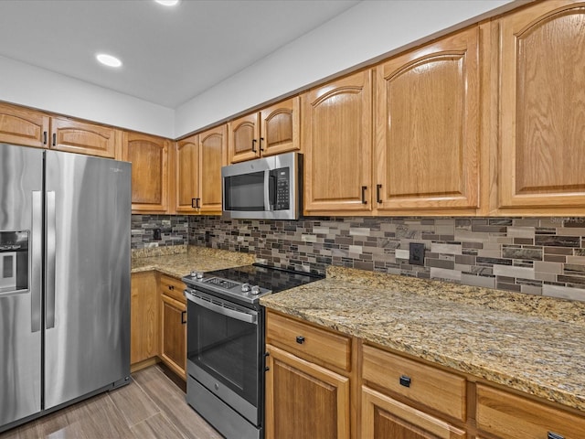 kitchen featuring backsplash, light stone countertops, light hardwood / wood-style flooring, and appliances with stainless steel finishes