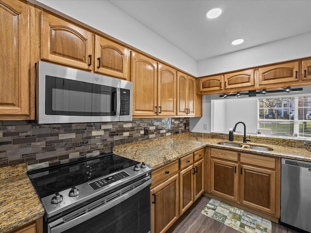 kitchen with backsplash, sink, dark hardwood / wood-style floors, light stone counters, and stainless steel appliances