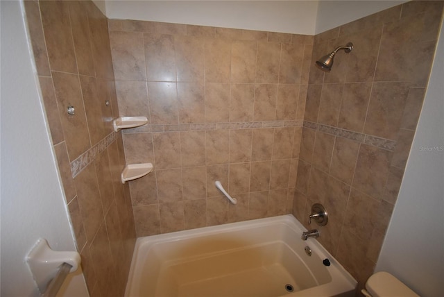 bathroom with toilet and tiled shower / bath