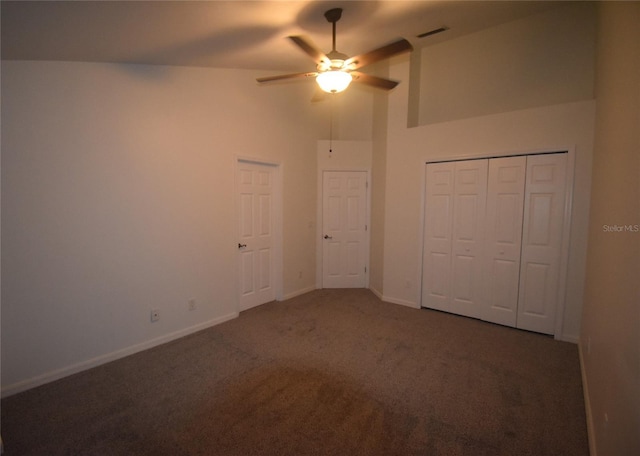 unfurnished bedroom with ceiling fan, dark carpet, high vaulted ceiling, and a closet