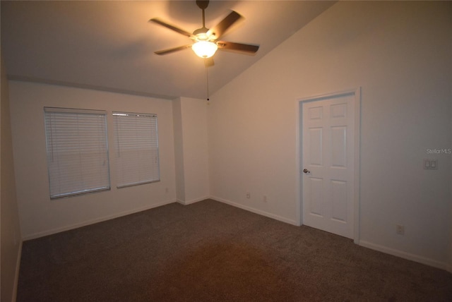 spare room with dark colored carpet, vaulted ceiling, and ceiling fan