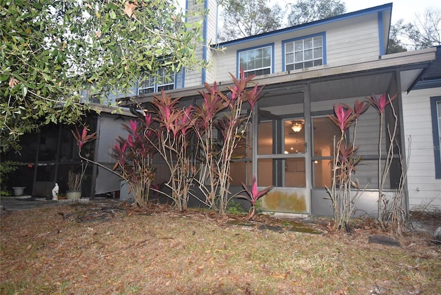 rear view of house with a sunroom and a lawn