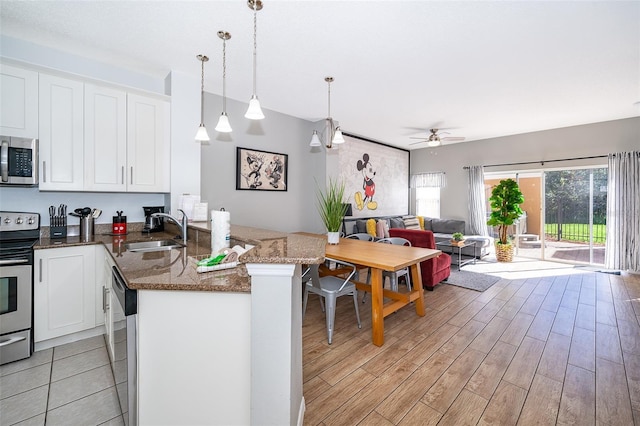 kitchen with kitchen peninsula, sink, decorative light fixtures, white cabinetry, and stainless steel appliances