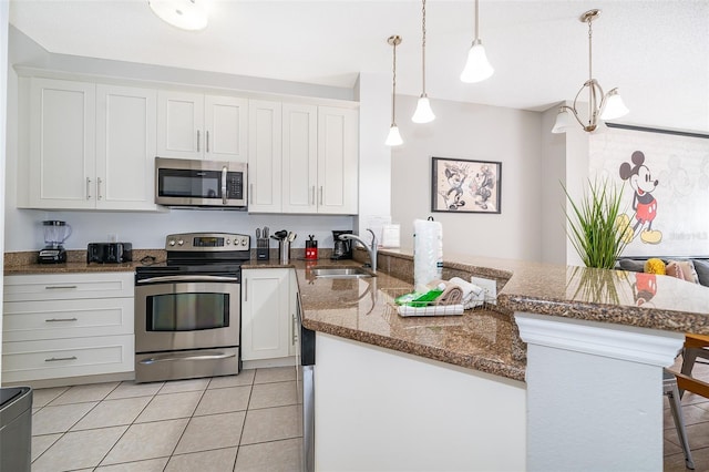 kitchen featuring a breakfast bar, stainless steel appliances, sink, white cabinets, and hanging light fixtures