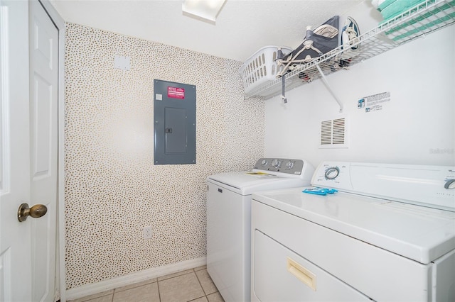 clothes washing area featuring washer and dryer, light tile patterned flooring, and electric panel