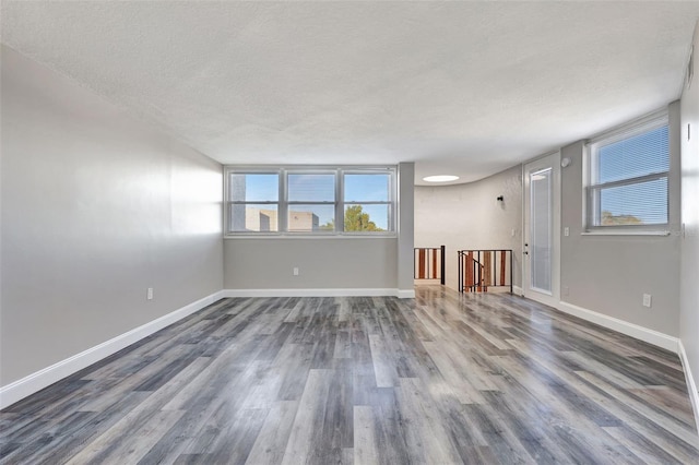 empty room featuring a textured ceiling and dark wood-type flooring