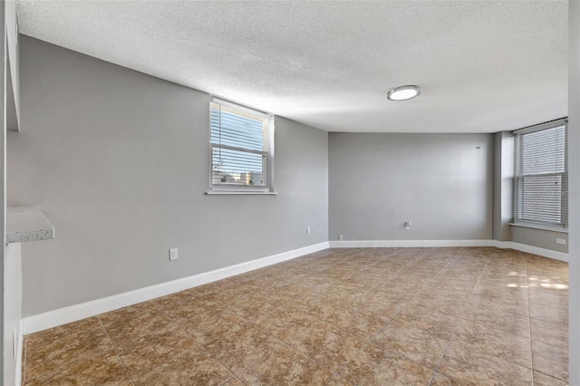 spare room with a textured ceiling and tile patterned floors