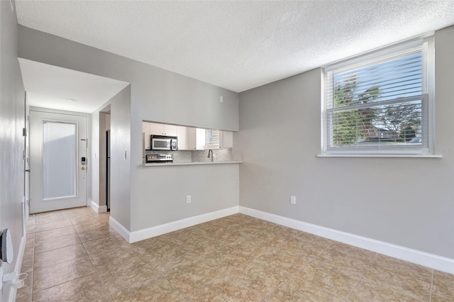 empty room featuring sink, light tile patterned flooring, and a textured ceiling