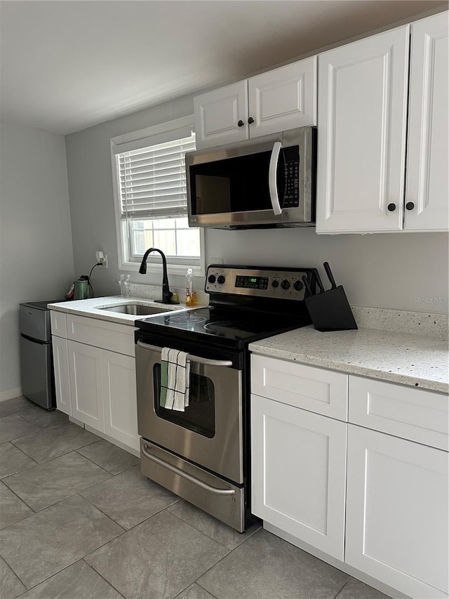 kitchen featuring appliances with stainless steel finishes, sink, light stone countertops, and white cabinets