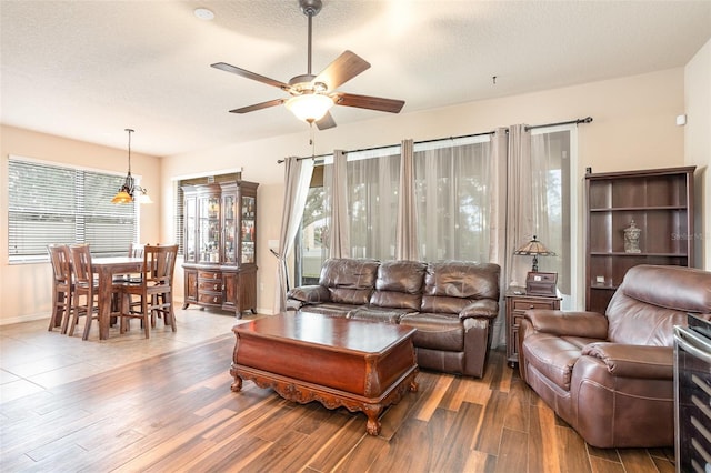 living room featuring ceiling fan, a textured ceiling, and dark hardwood / wood-style flooring