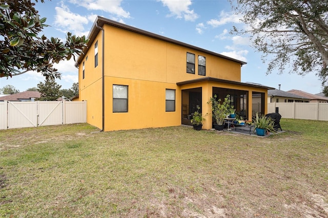 back of house featuring a sunroom and a lawn