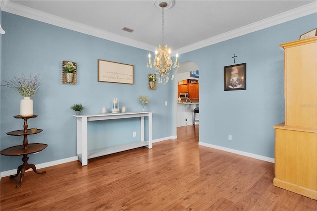 unfurnished dining area with light hardwood / wood-style floors, crown molding, and a notable chandelier