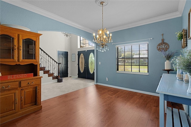 foyer featuring hardwood / wood-style flooring, crown molding, and a chandelier