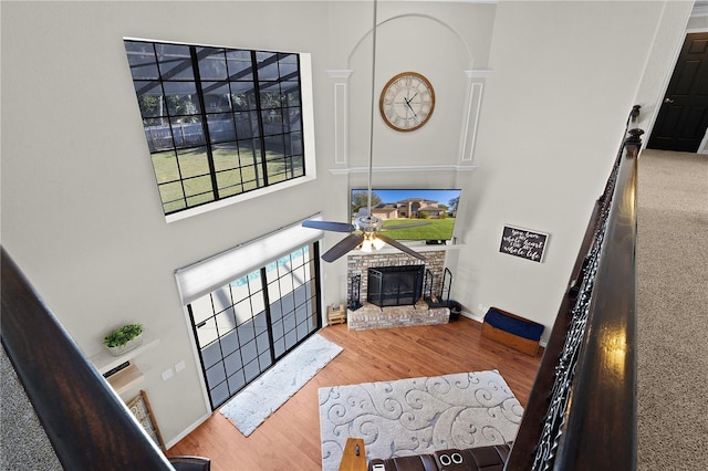 living room featuring hardwood / wood-style floors, a towering ceiling, and a brick fireplace