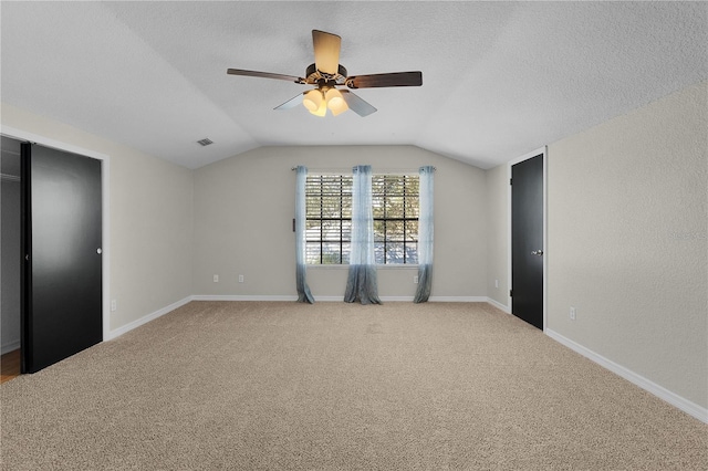 unfurnished bedroom with carpet, ceiling fan, a textured ceiling, and vaulted ceiling