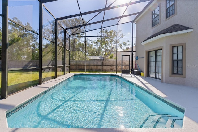 view of pool featuring a lawn, glass enclosure, and a patio area