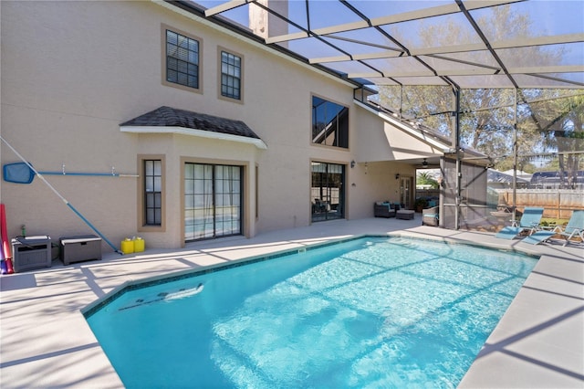 view of swimming pool featuring glass enclosure and a patio area