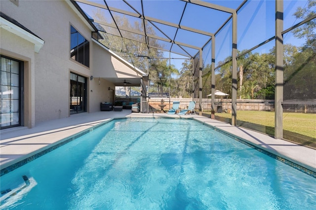 view of pool with a lawn, ceiling fan, a patio area, and glass enclosure