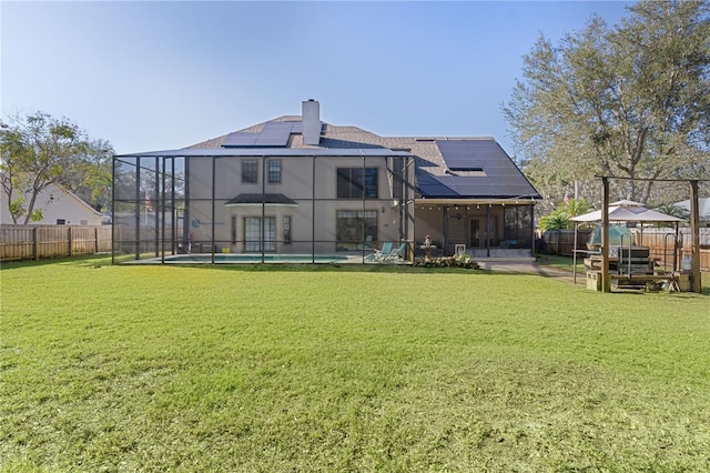 back of property with a fenced in pool, a lawn, a gazebo, and solar panels