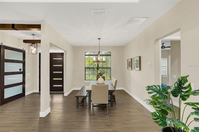 dining area featuring beam ceiling, dark wood-type flooring, and a chandelier