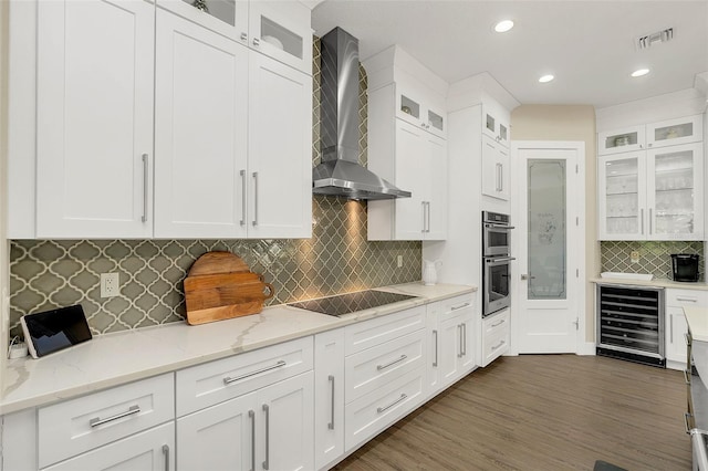 kitchen with visible vents, beverage cooler, white cabinetry, wall chimney range hood, and black electric cooktop