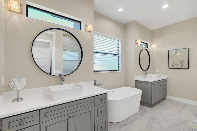 full bath with a freestanding bath, recessed lighting, marble finish floor, and a sink