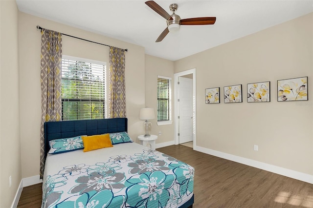 bedroom with a ceiling fan, wood finished floors, and baseboards