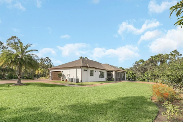 rear view of property with a lawn, central AC unit, and a garage