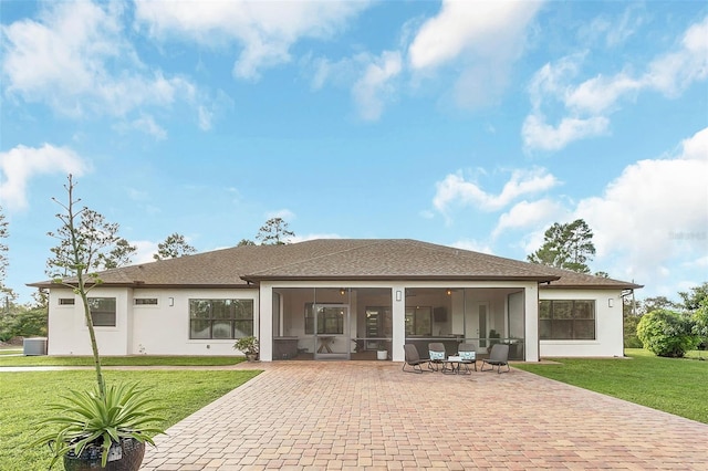 rear view of property featuring a patio area, stucco siding, a yard, and a sunroom