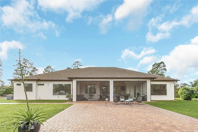 back of property featuring a patio area, a lawn, a sunroom, and stucco siding