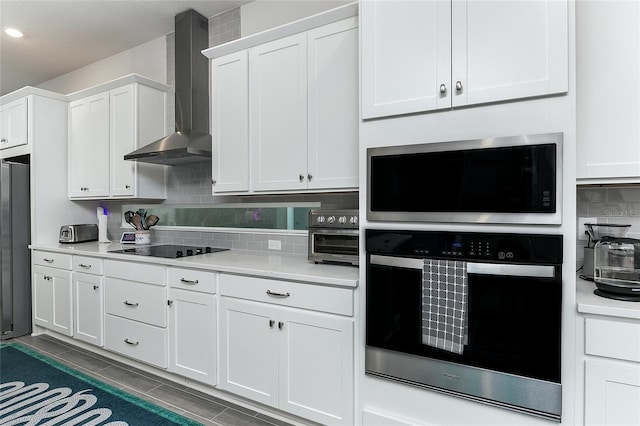 kitchen with wall chimney exhaust hood, decorative backsplash, white cabinetry, and stainless steel appliances