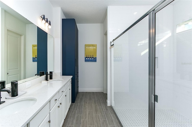 bathroom with a shower with door, vanity, and a textured ceiling