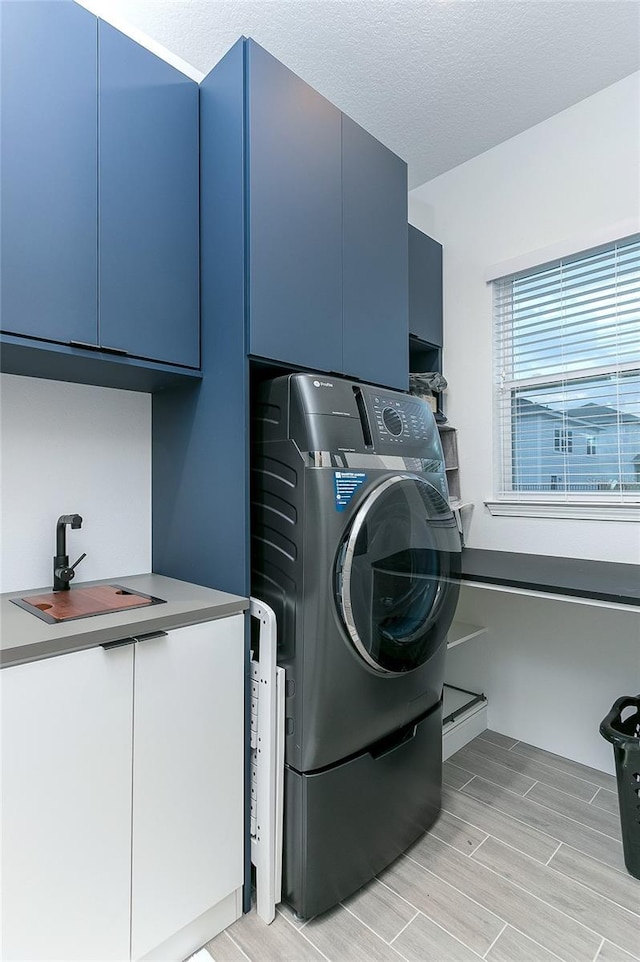 washroom with washer / clothes dryer, sink, cabinets, and a textured ceiling