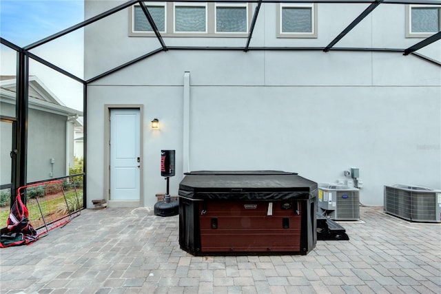 view of patio / terrace featuring central AC unit, a lanai, and a hot tub