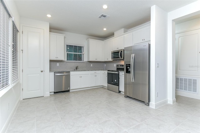 kitchen with appliances with stainless steel finishes, tasteful backsplash, white cabinetry, and sink